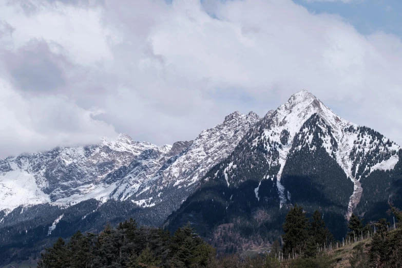 a large snow covered mountain sitting under a cloudy sky