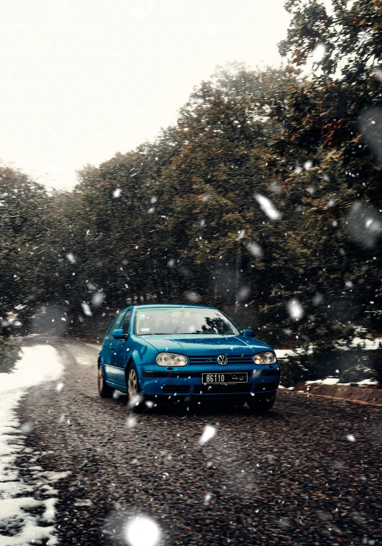 a blue car sitting on the side of a road next to trees