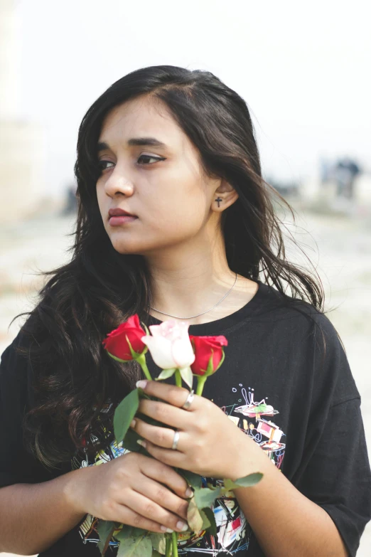 a girl wearing a t - shirt holding two roses in her hands