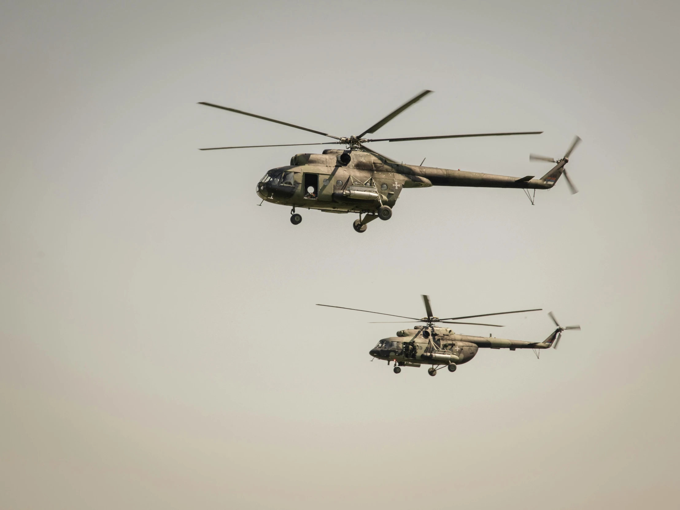 two large military helicopters flying in the sky