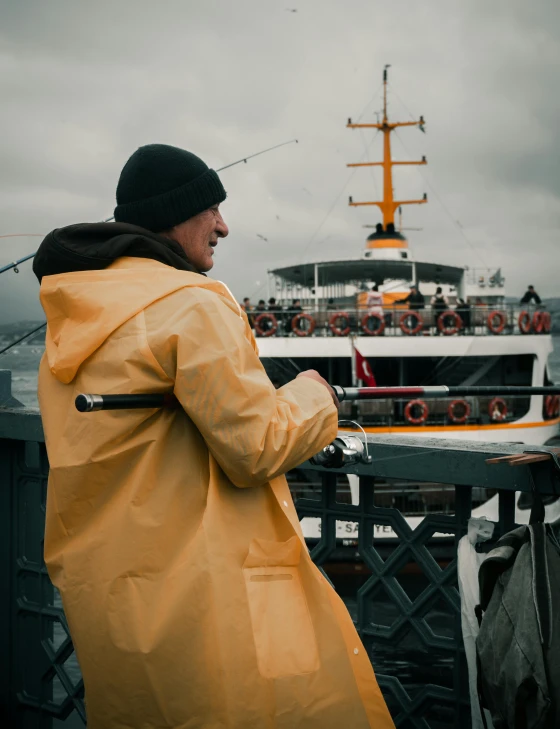 a woman in yellow coat standing next to water with boat