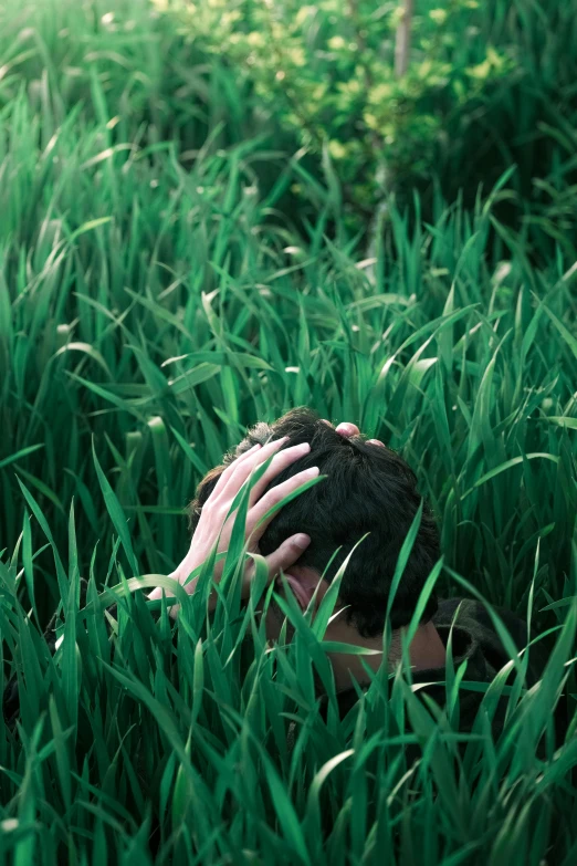 person covering head in grassy field with hands