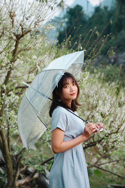 a girl standing outside holding a clear umbrella