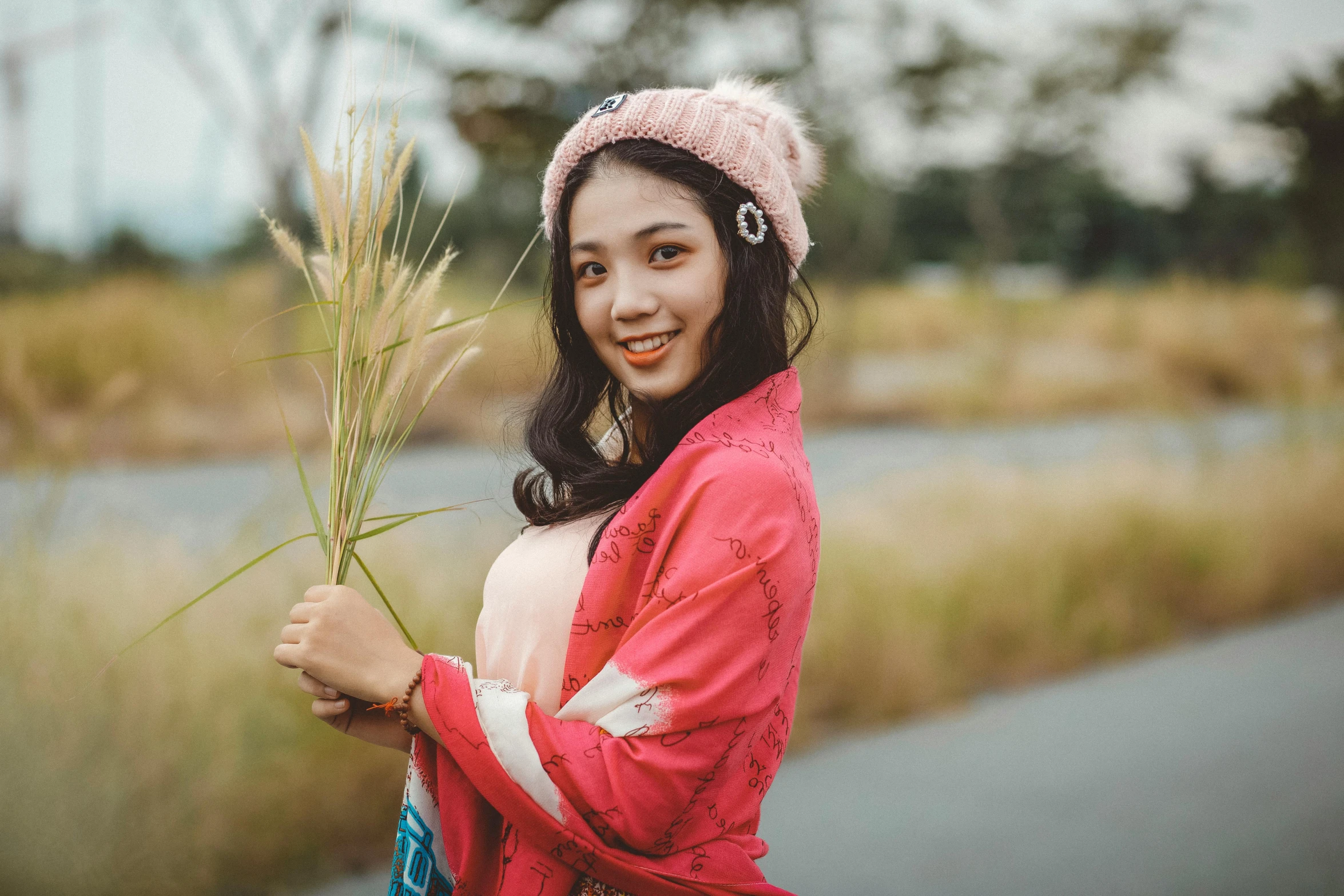 a girl holding a long stalk of grass