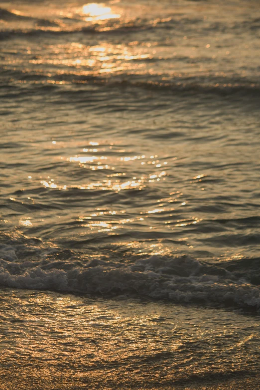 water splashing from the shore as the sun sets in the distance