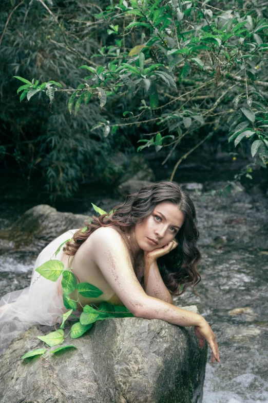 a young woman is sitting on a rock in the water