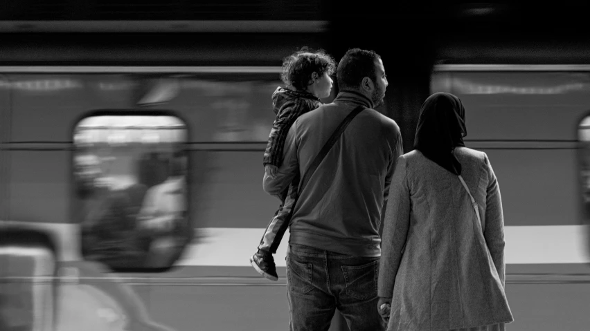 a group of people are standing on a platform waiting for the train