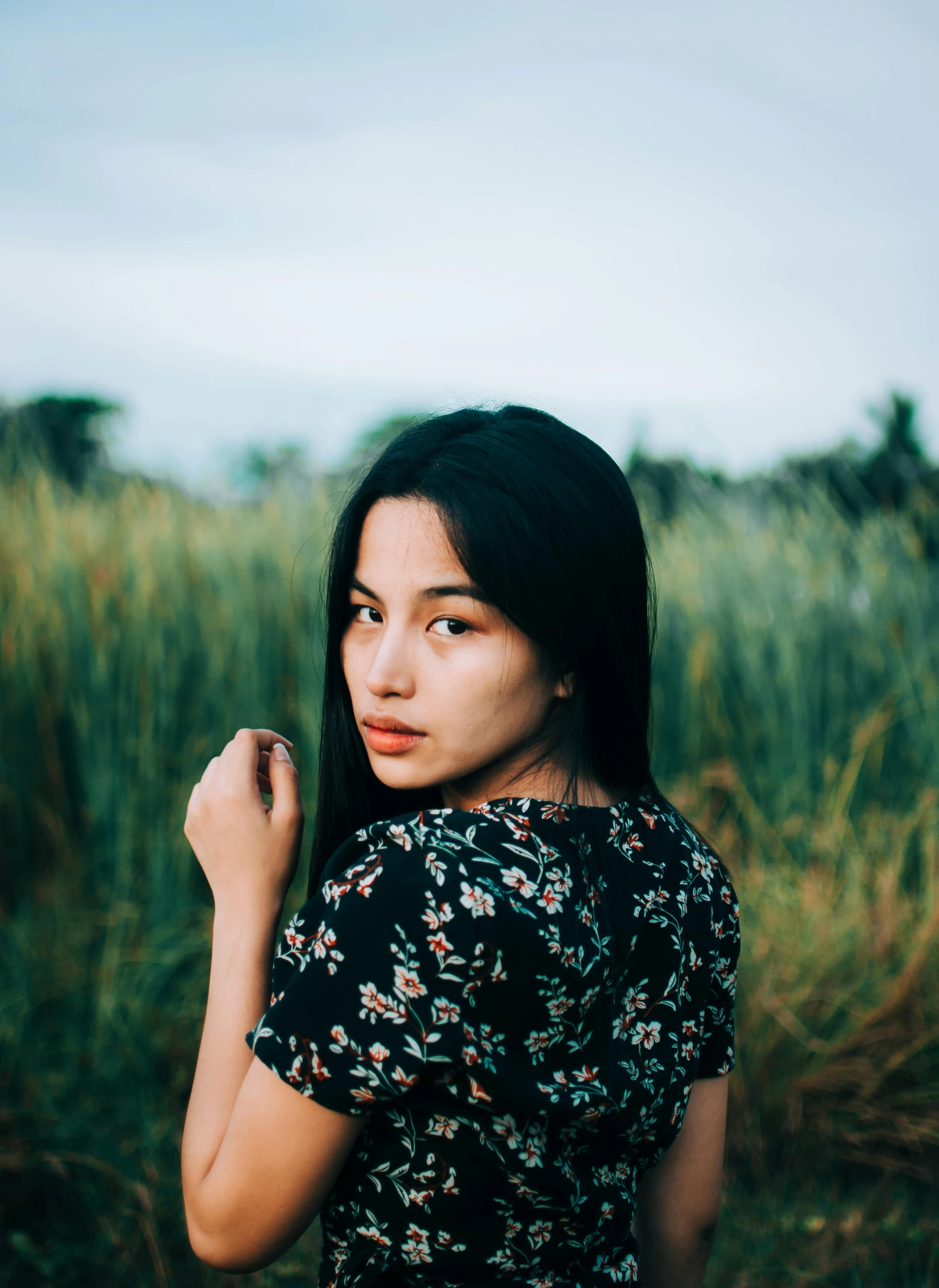 a girl in a floral dress standing near a field