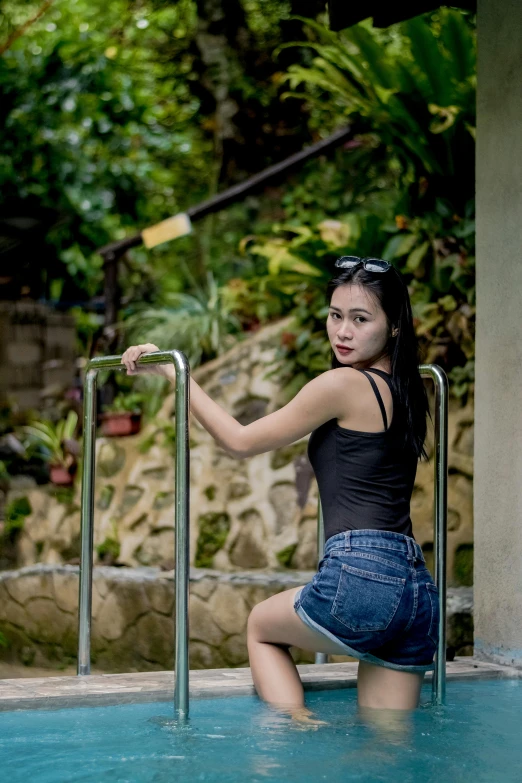 the young lady is sitting at the edge of the pool