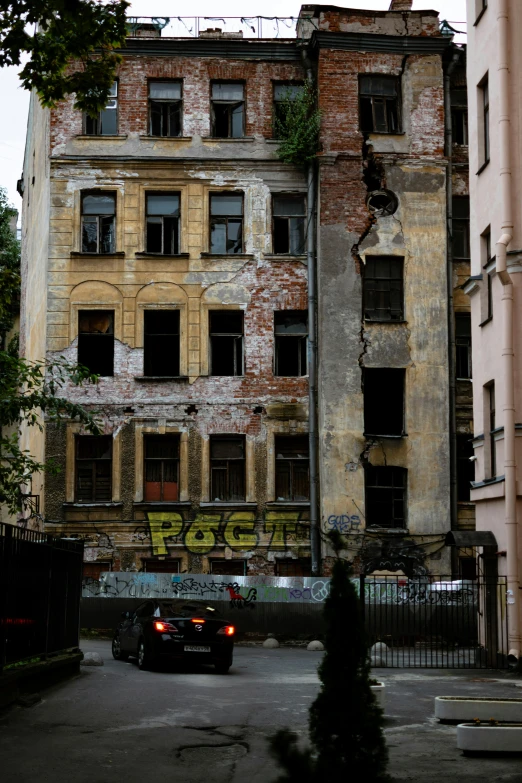 an abandoned building with graffiti and a car in front