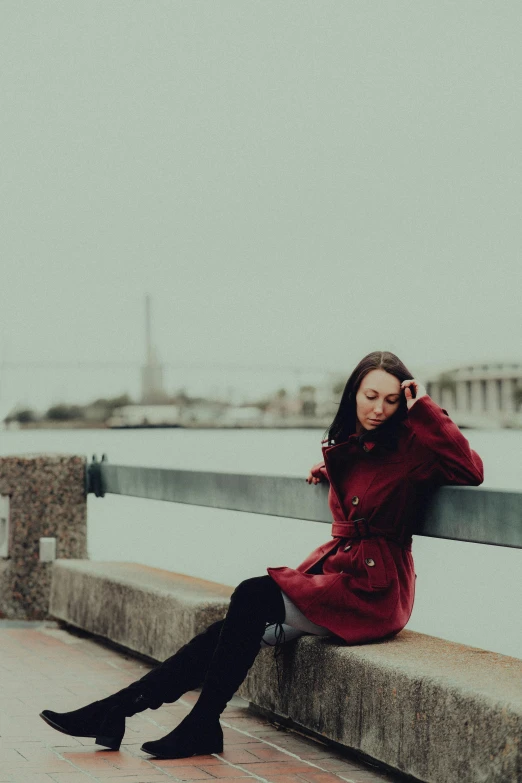 a young woman wearing boots while sitting on a rail