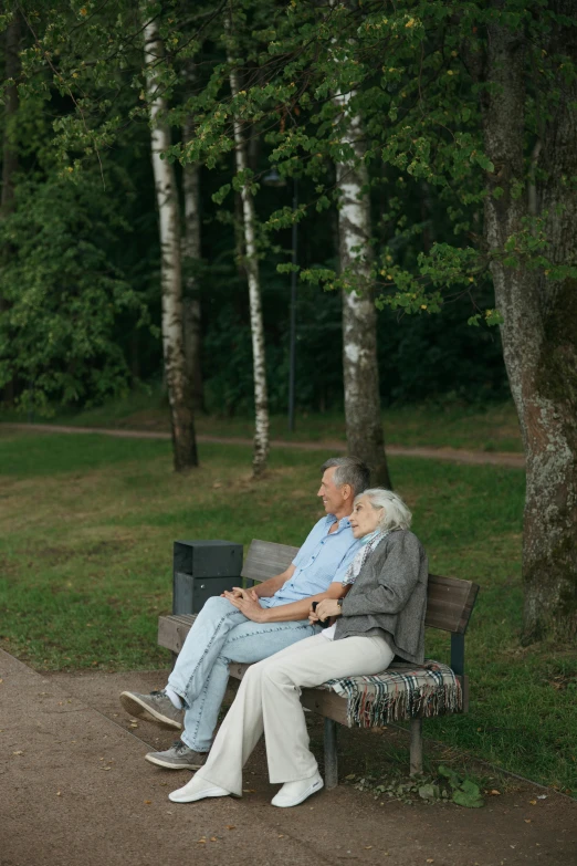 two elderly people sitting on a park bench