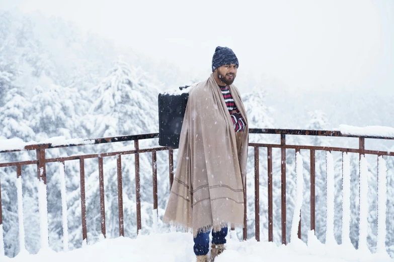 a man stands with his luggage on a snowy balcony