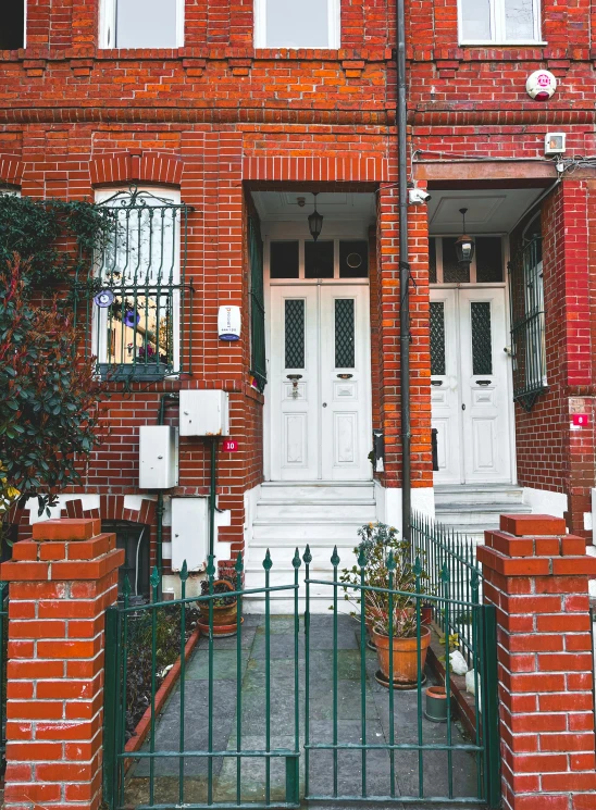 an orange brick building with two white doors and two white windows