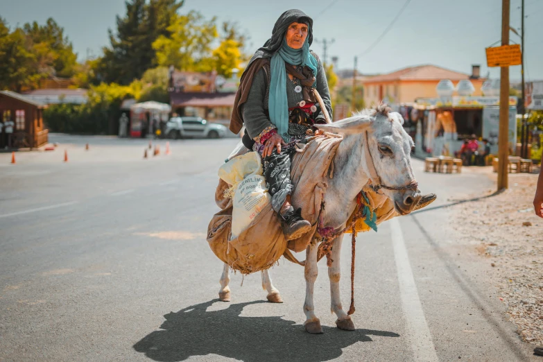 a person riding a small bull down the middle of a road