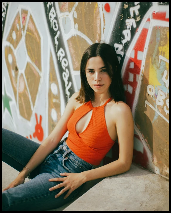 a woman wearing an orange shirt is sitting on the concrete