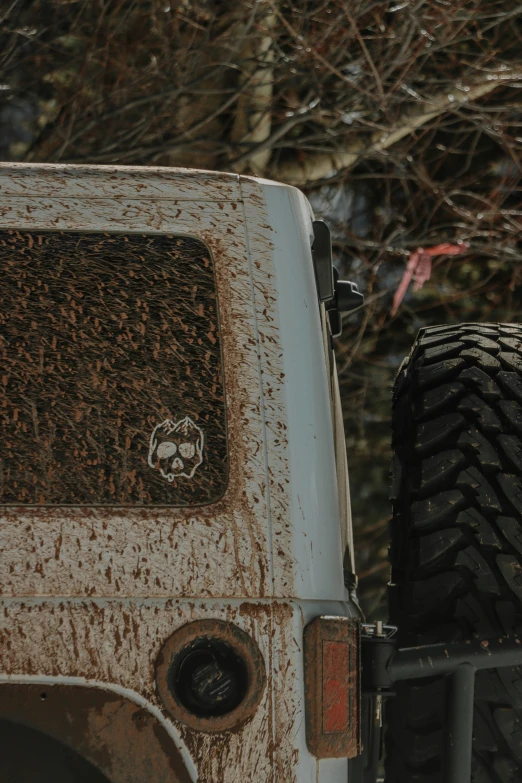 an old rusted car with a tire next to some trees