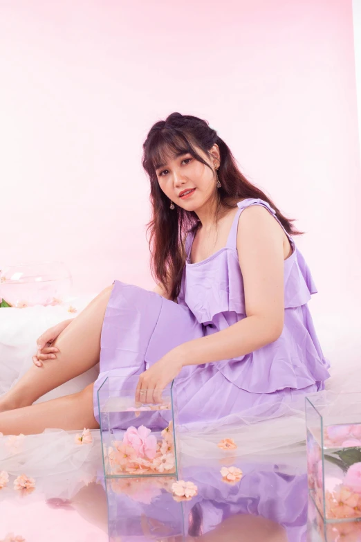 an asian woman is sitting in her purple gown and some flowers