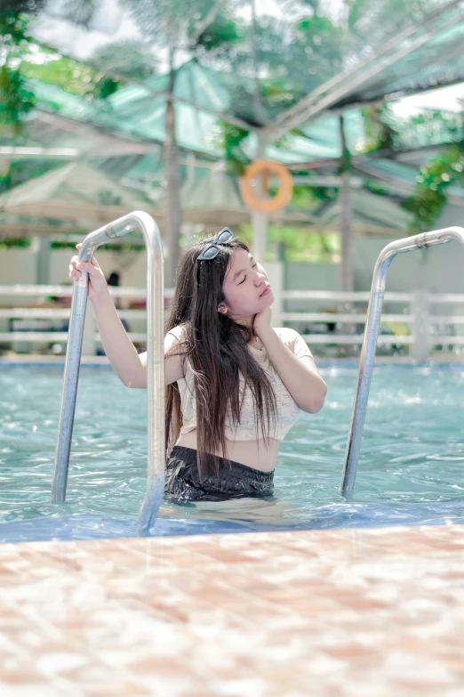 a girl is standing in the water near a set of ladders