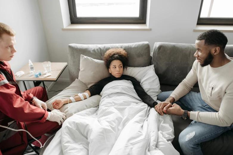 a woman on a couch with a man watching her as she lays in bed