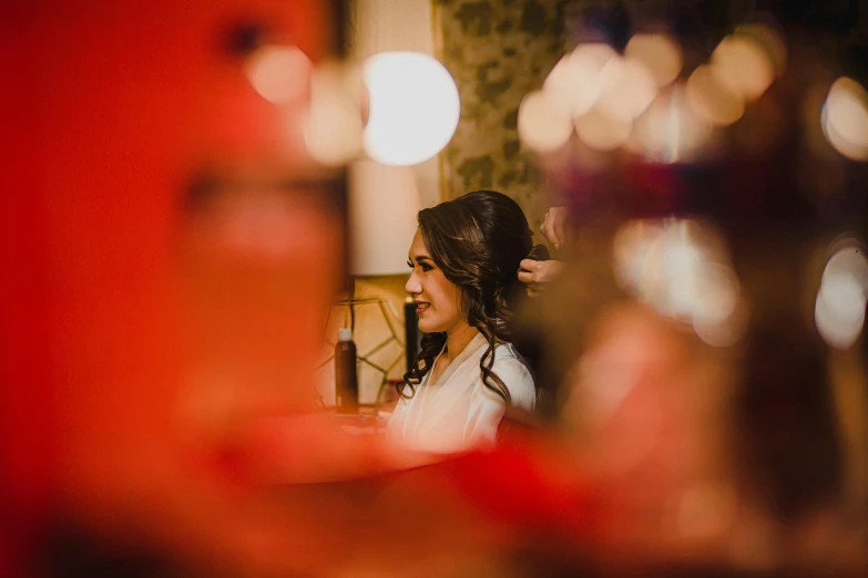 a woman with long dark hair in a white dress getting her hair styled