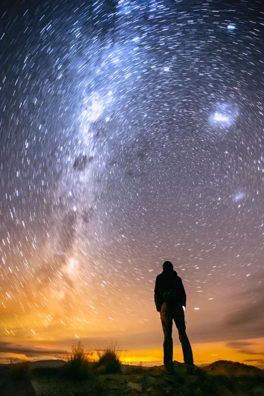 a person standing on top of a hill under the stars