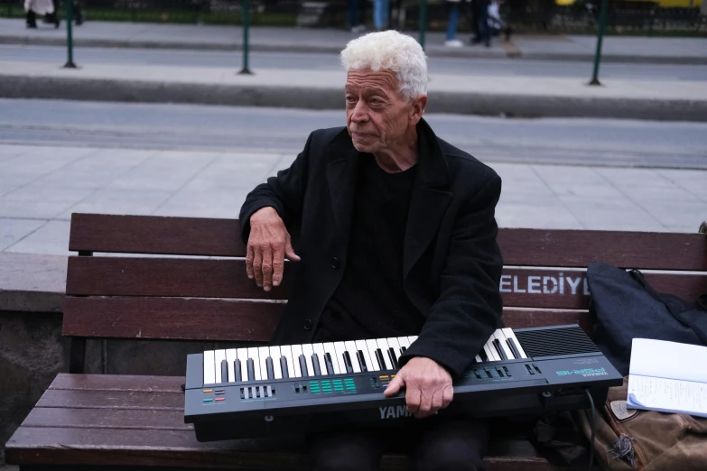 a man sitting on top of a bench next to an electronic keyboard