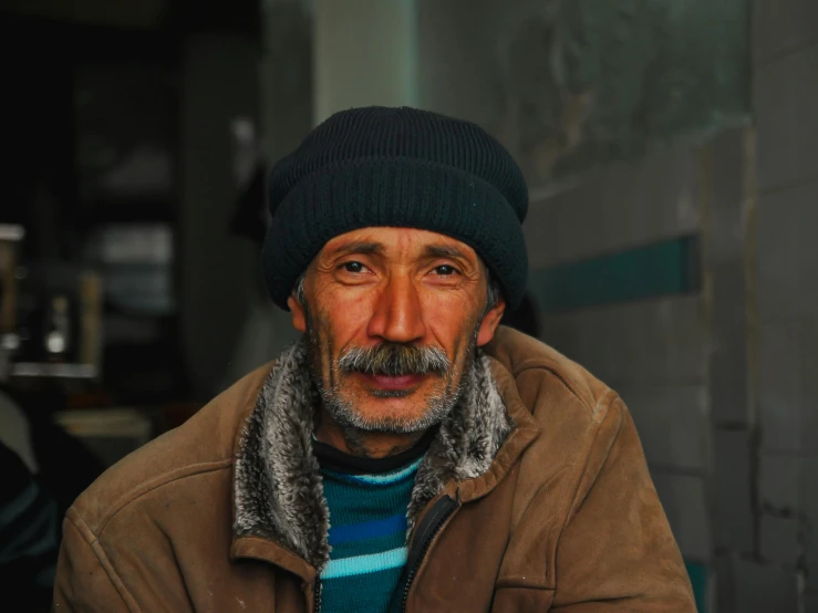 a man is sitting outside wearing a hat and jacket