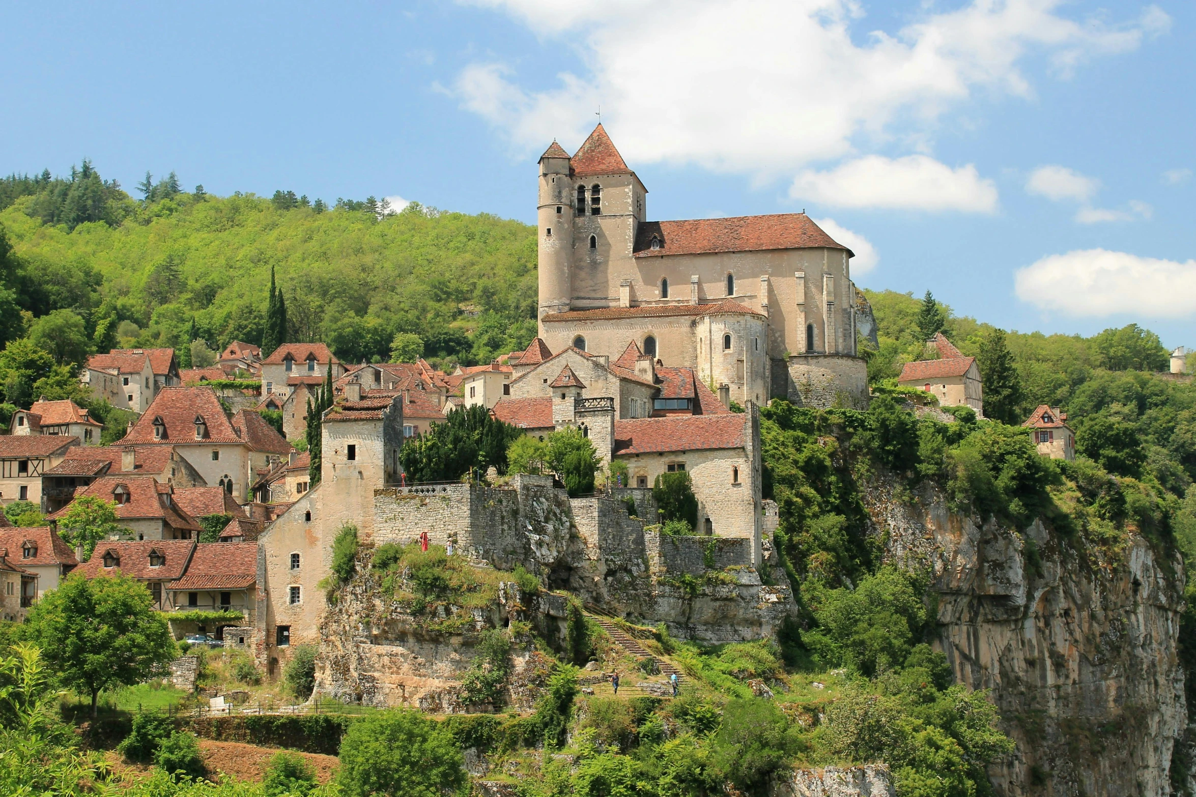 a castle with red brick roofs atop the hillside