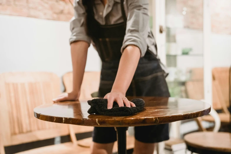 woman wiping down table cloth on top of table