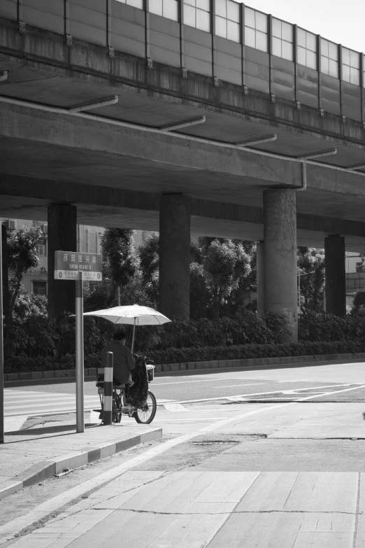 black and white image of an umbrella and bicycle with water in the background