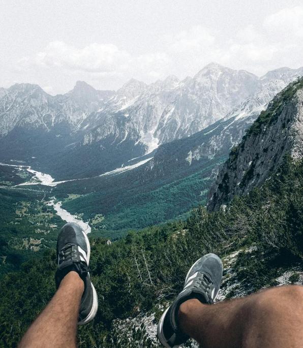 a person's legs in the air on top of a mountain