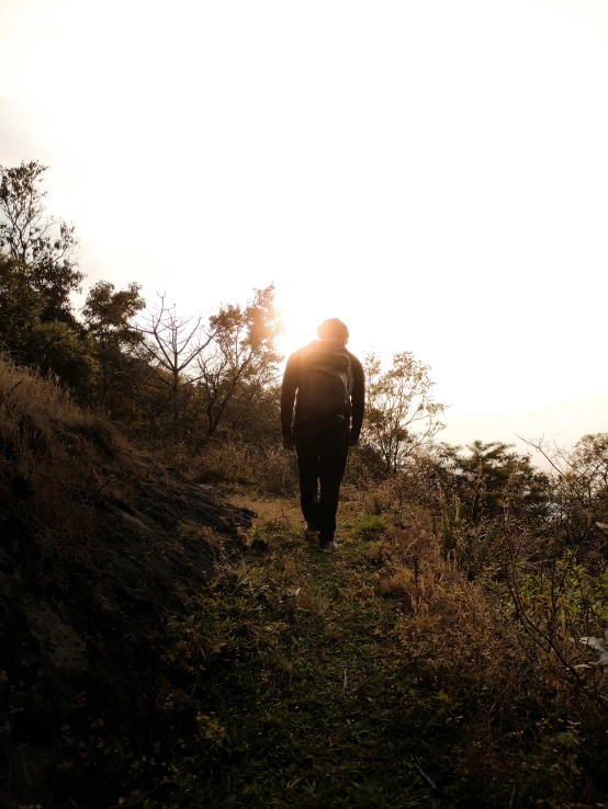 a man walks up a hill near the sun