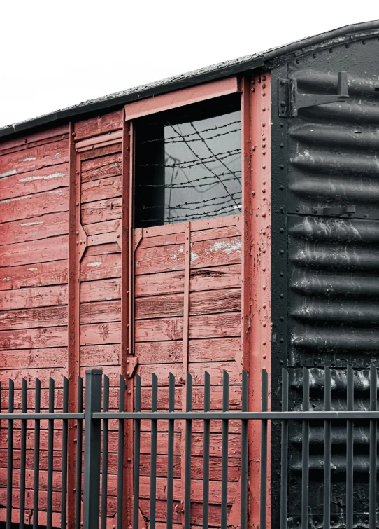 a black gate stands in front of a red boxcar