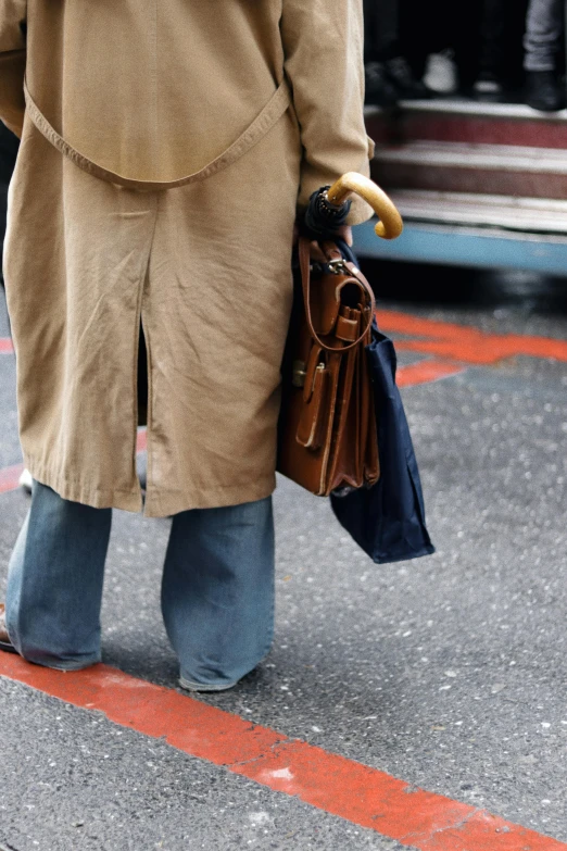 a person carrying bags and umbrellas on the sidewalk