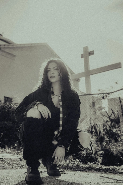 a person kneeling on a curb with a cross in the background