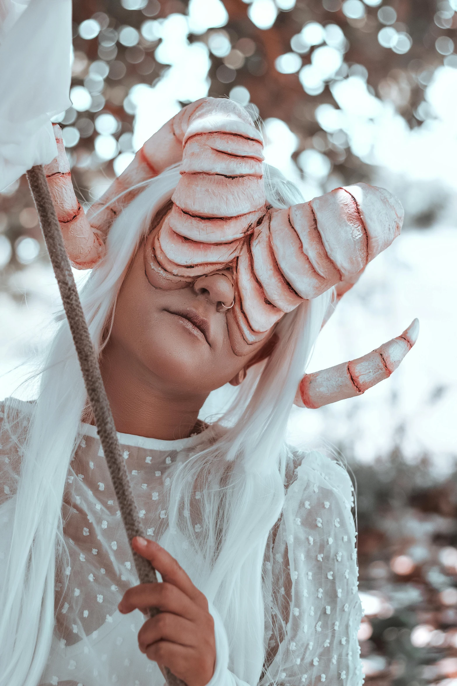 a woman with a pink icing covered face holds an umbrella in a snowy scene