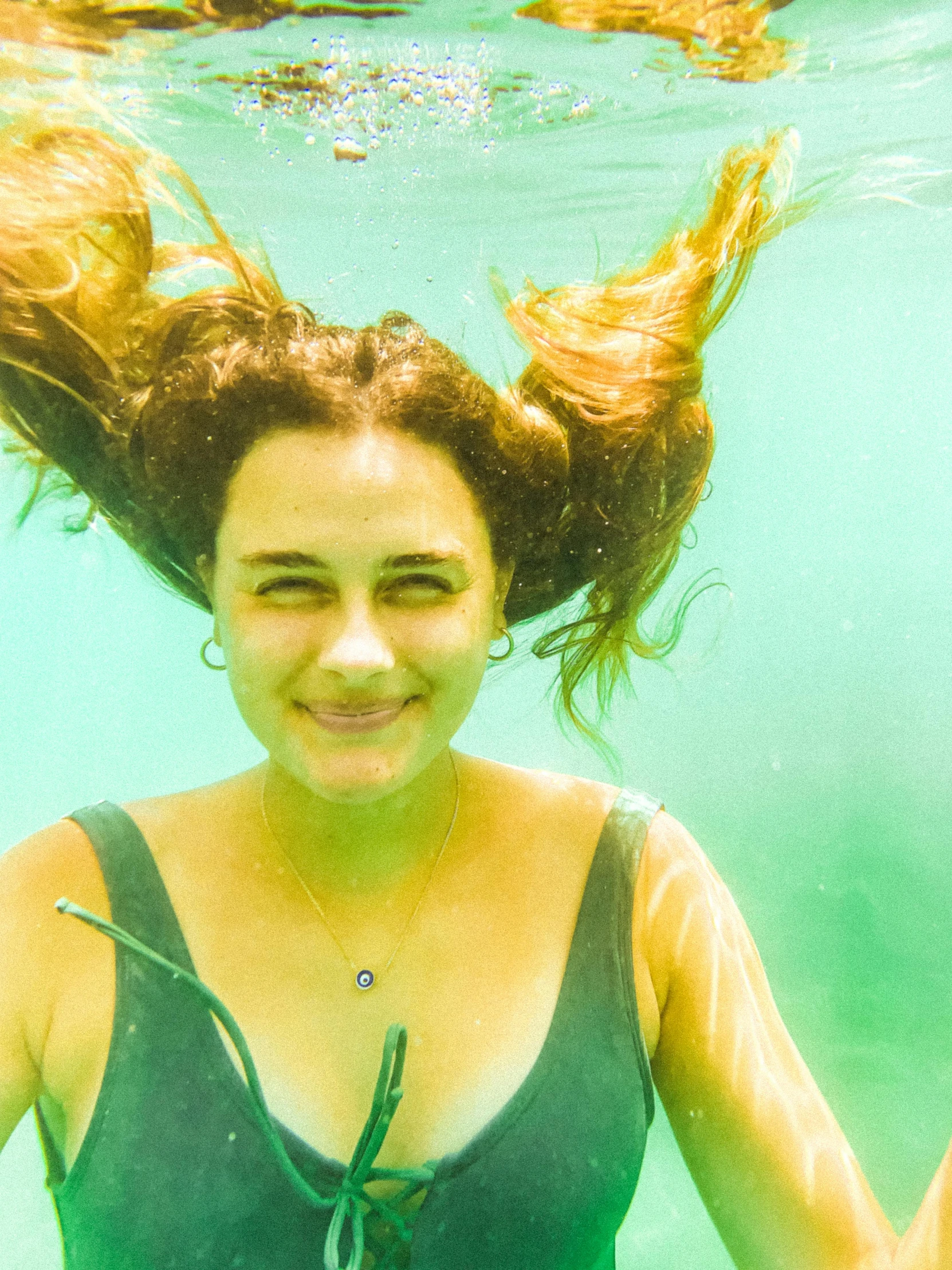 a woman smiling in the water as she floats down a river