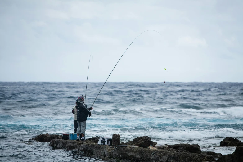 a person fishing on a rock by the ocean