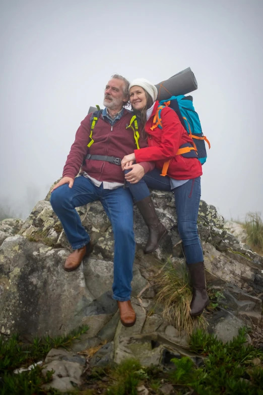 an older couple sitting on a rock in the woods