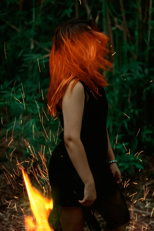 a woman with red hair walking around the fire