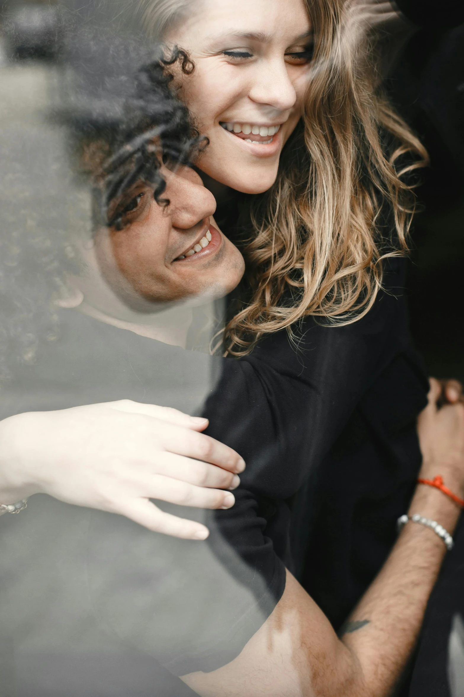 a man and woman taking a selfie from behind a glass