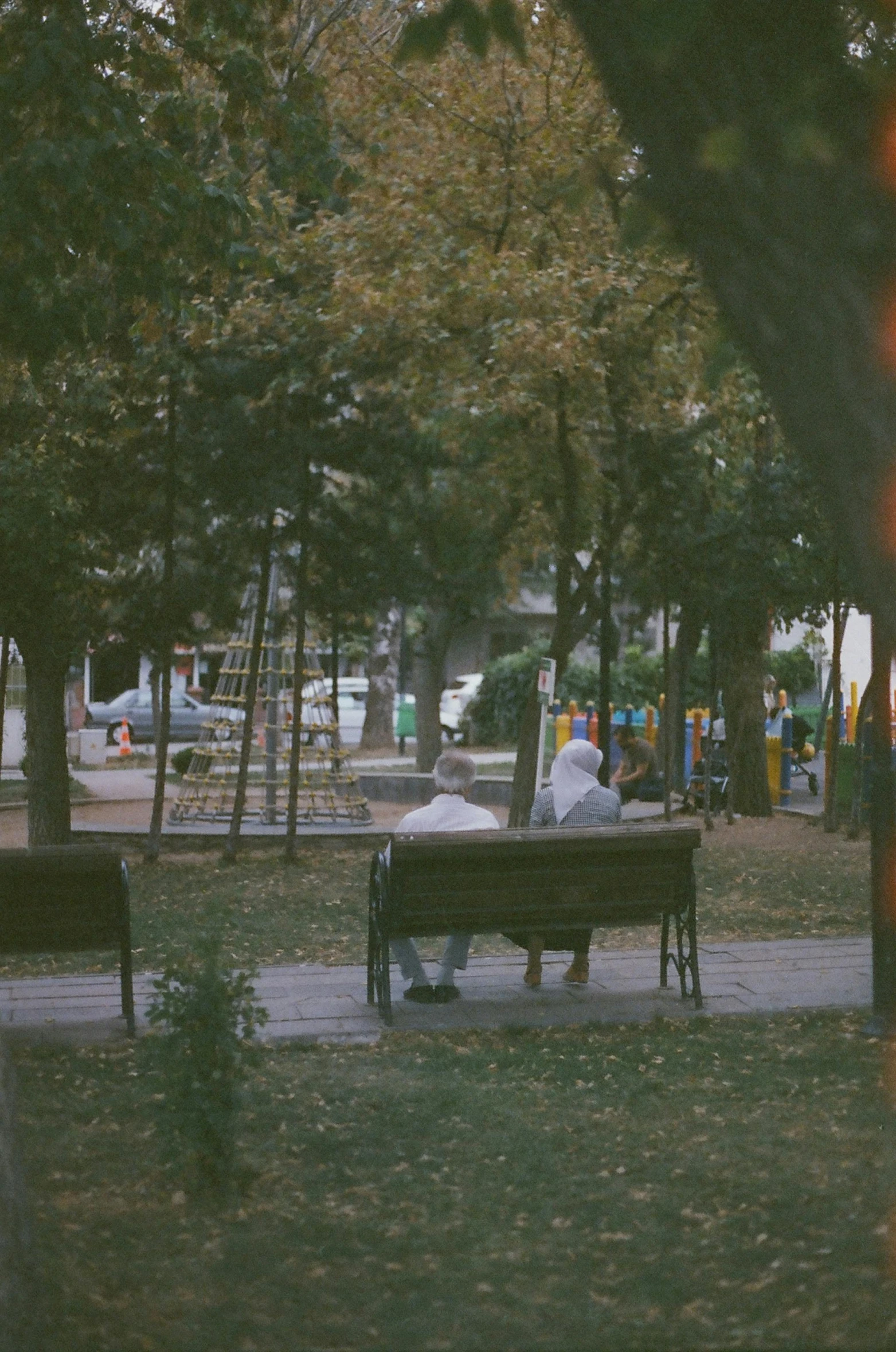 a man sitting on top of a bench in a park