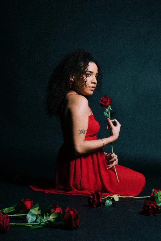 a woman is holding a rose while sitting on the floor