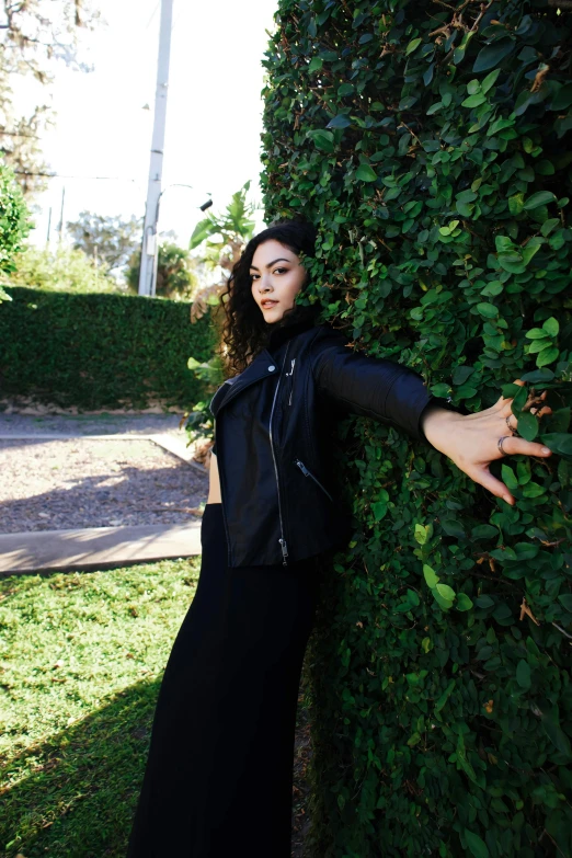 a woman poses for a po in front of a hedge