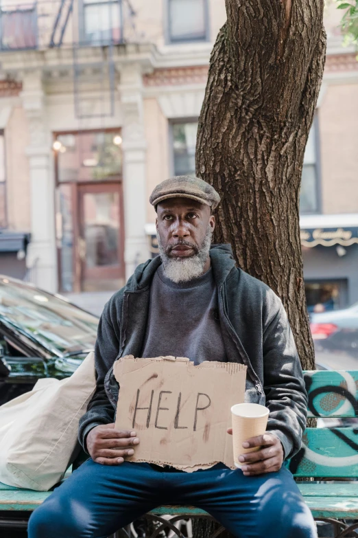 a homeless man holding a sign on the sidewalk