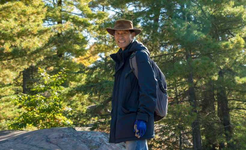 a man stands in front of a tree filled forest