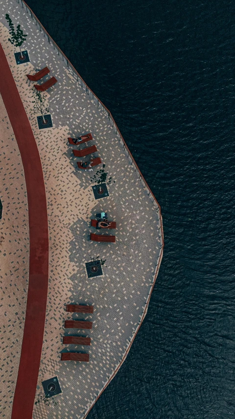 the aerial view shows red flags lined on top of a sandy area near water