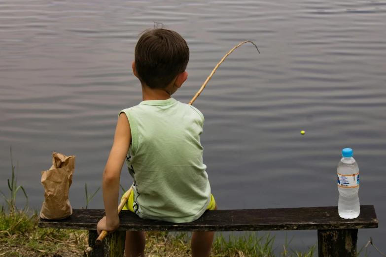 a  is sitting on the bench with his rod by a river