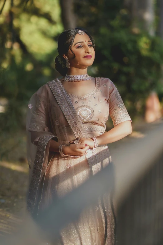 a lady in a white sari walking next to a fence